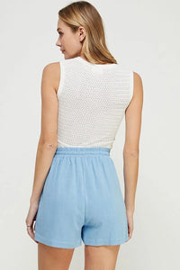 Woman wearing a white fine gauge tank top with mixed pointelle details and blue shorts
