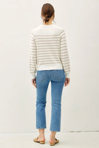 Woman wearing lightweight striped long sleeve sweater with light blue cropped jeans and open-back flats