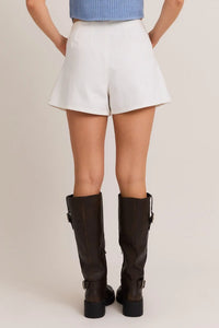 Woman wearing PLEATED DETAIL DENIM SHORT with brown boots, ideal for women’s boho chic clothing