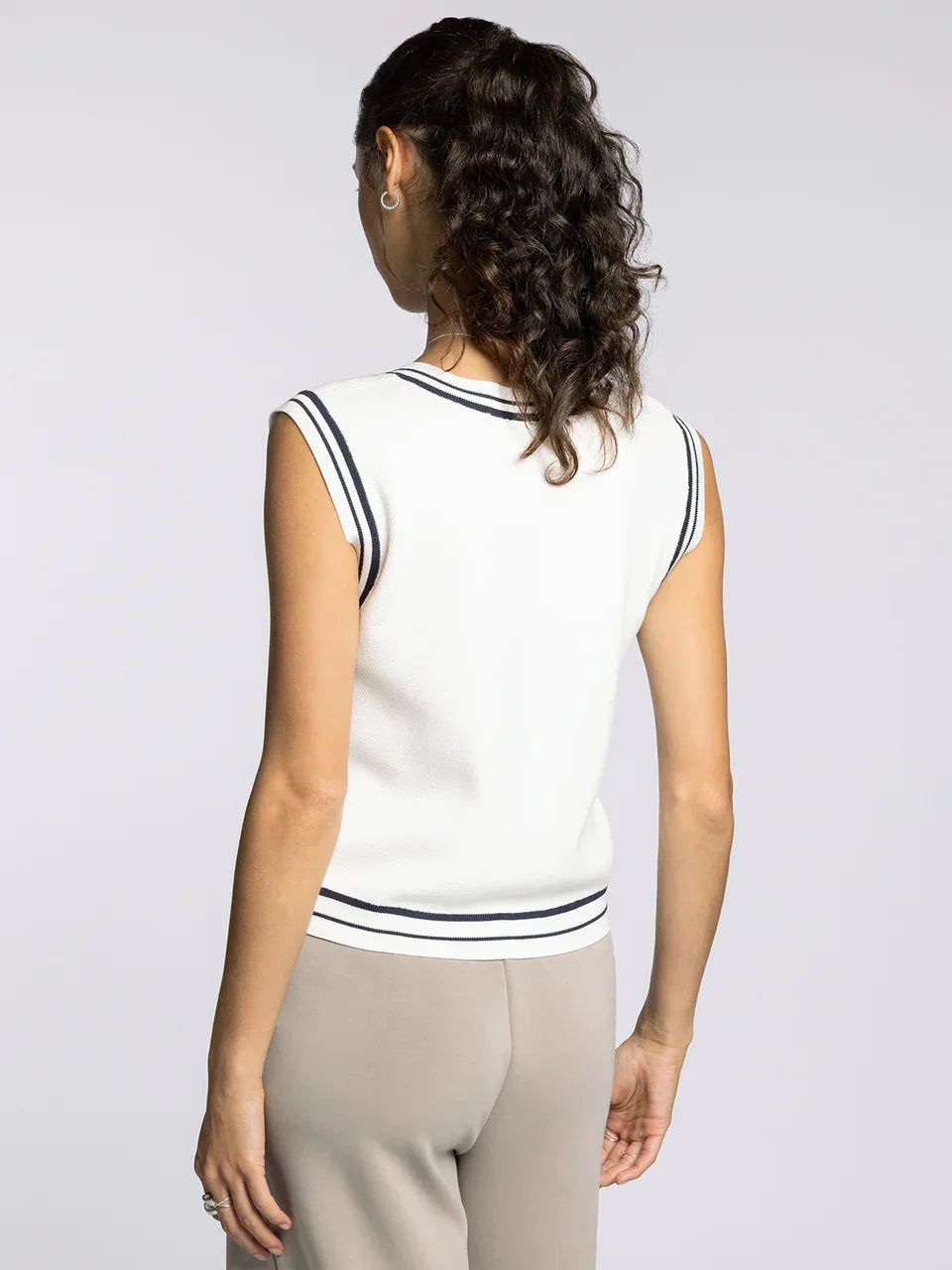 Woman wearing white sleeveless knit top with navy stripes, part of the Supply Jessie collection