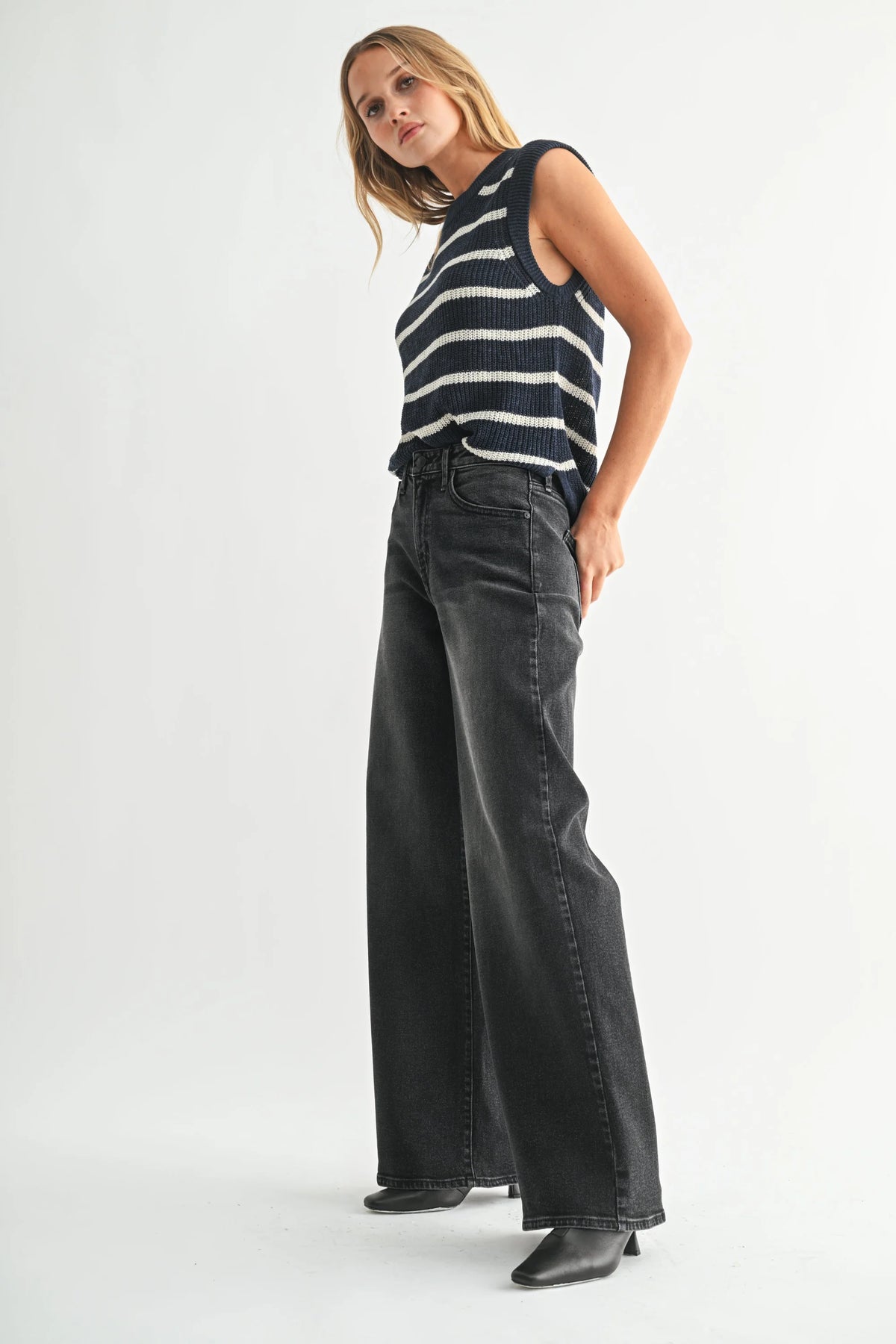 Women’s black and white striped sleeveless sweater with high-rise wide-leg bohemian denim jeans