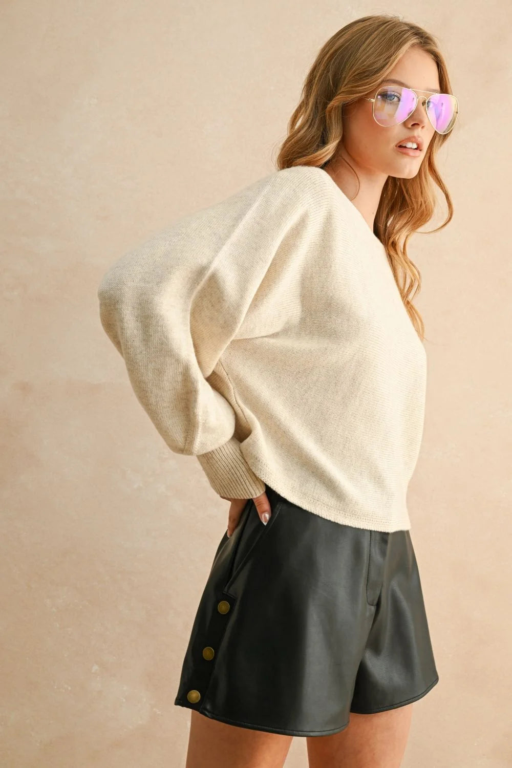 Women’s cream boat neck sweater with black faux leather shorts for stylish casual wear