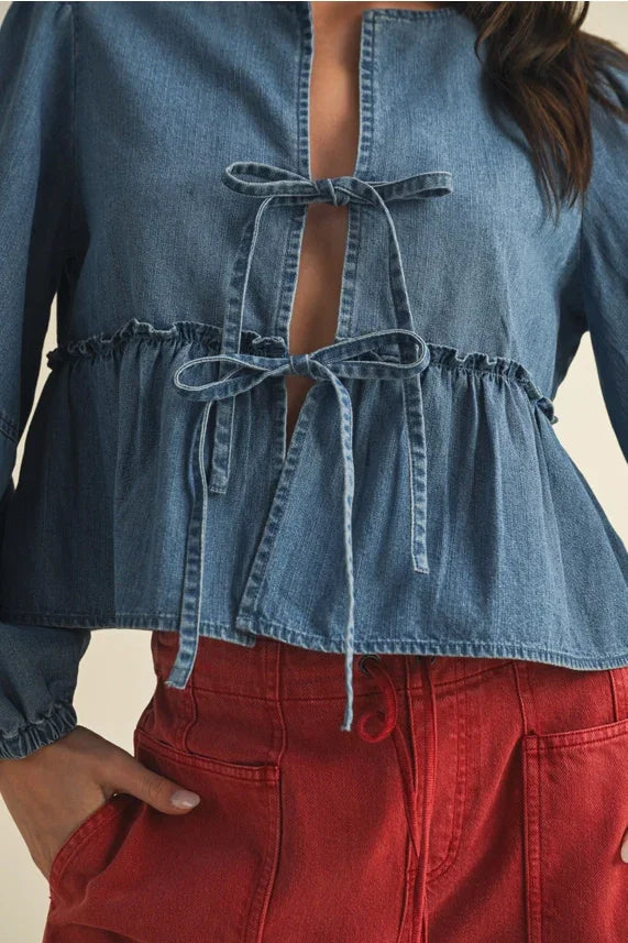 Women’s light blue denim peplum top with ruffle hem and tie closure details