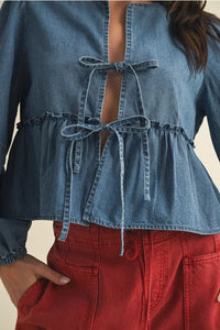 Women’s light blue denim peplum top with ruffle hem and tie closure details