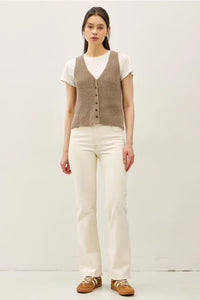 Women’s light brown chunky v neck sweater vest with neck button over white t-shirt