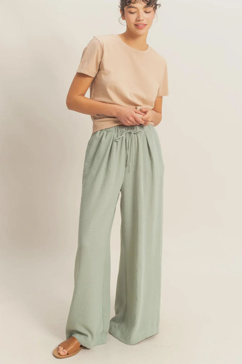 Women wearing light brown t-shirt and green wide-leg pants with elasticized waist