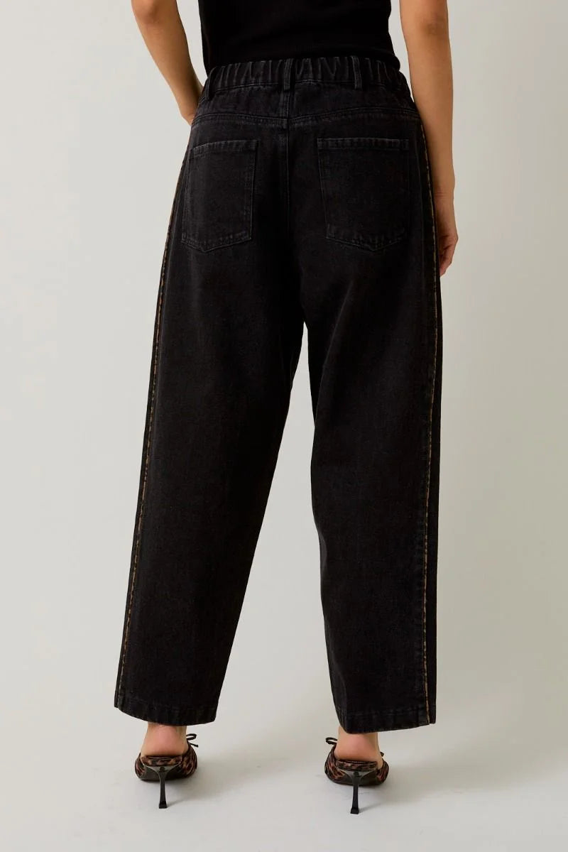 Women’s loose-fit black jeans with leopard print piping and visible white stitching