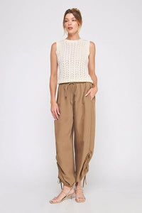 Women’s sleeveless cream knit top with brown drawstring pants and sandals in adjustable scrunch jogger style