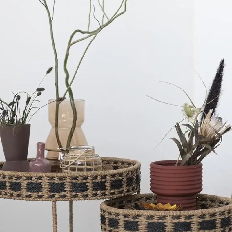 Woven rattan nesting tables with decorative bands next to a Glass Rattan Wrapped Tealight Holder