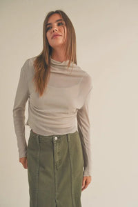 Young woman in beige turtleneck and olive green skirt wearing Women’s Boho Chic Clothing