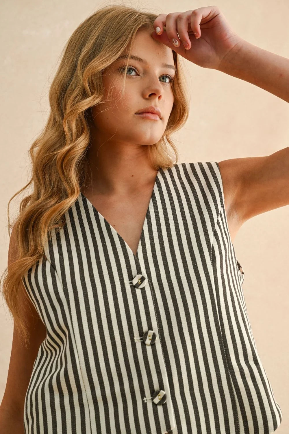 Young woman wearing a striped button front vest, perfect for women’s boho chic clothing at Shop Daisy