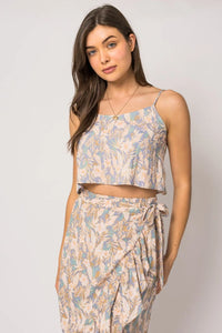 Young woman in a sleeveless floral tank top with matching skirt, showcasing summer style