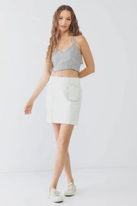 Young woman in a gray crop top and white skirt, exuding boho free spirit style