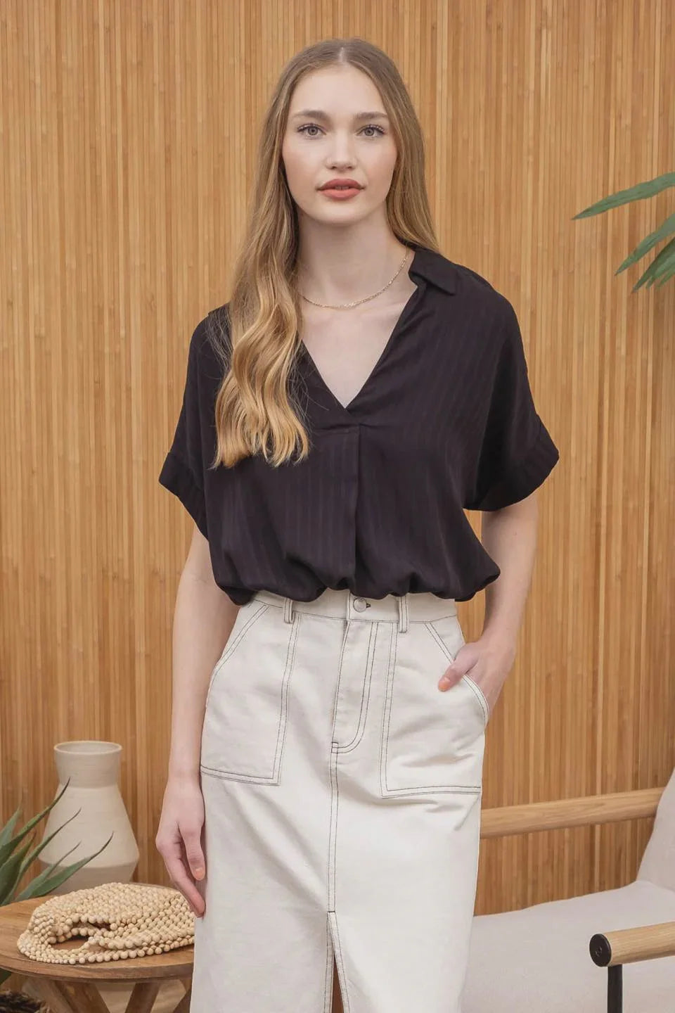 Young woman in a striped collared split neck blouse with long blonde hair