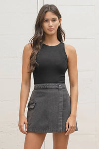 Young woman in a sleeveless black sweater knit tank and gray mini skirt