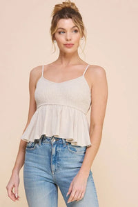 Young woman in white cami tank babydoll and blue jeans showcasing trendy style