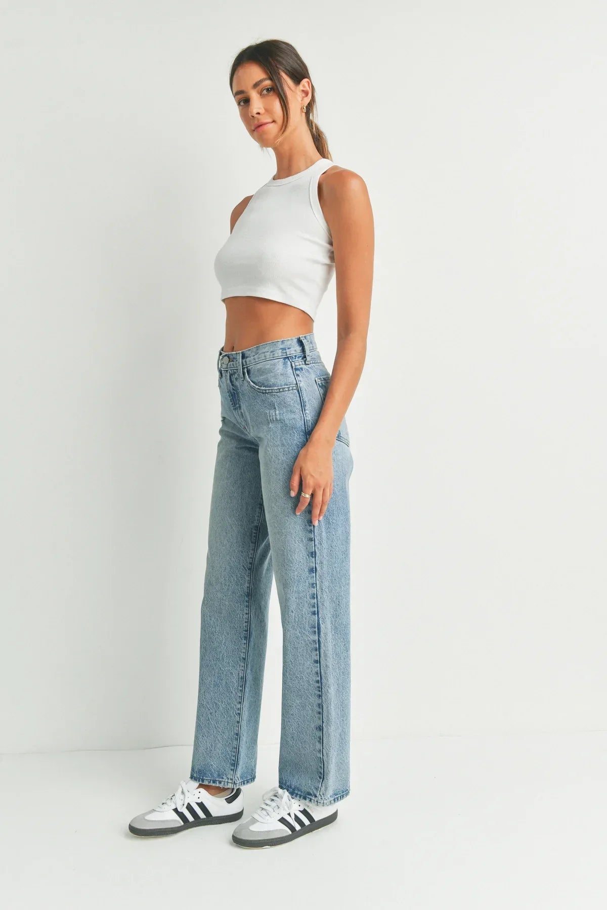 Young woman in a white crop top and light blue jeans embodies boho free spirit style