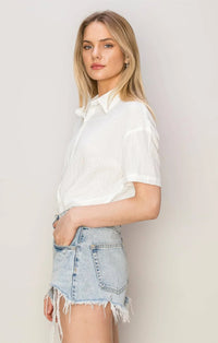 Young woman in white flowy shirt and denim shorts showcasing boho style