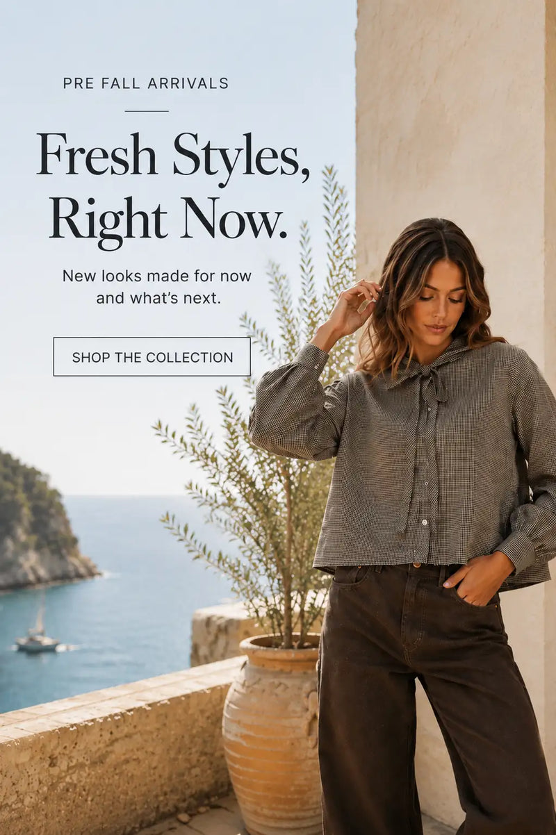 A woman wears a gray, long-sleeved button-up blouse with a subtle textured pattern and a tie-neck detail.
