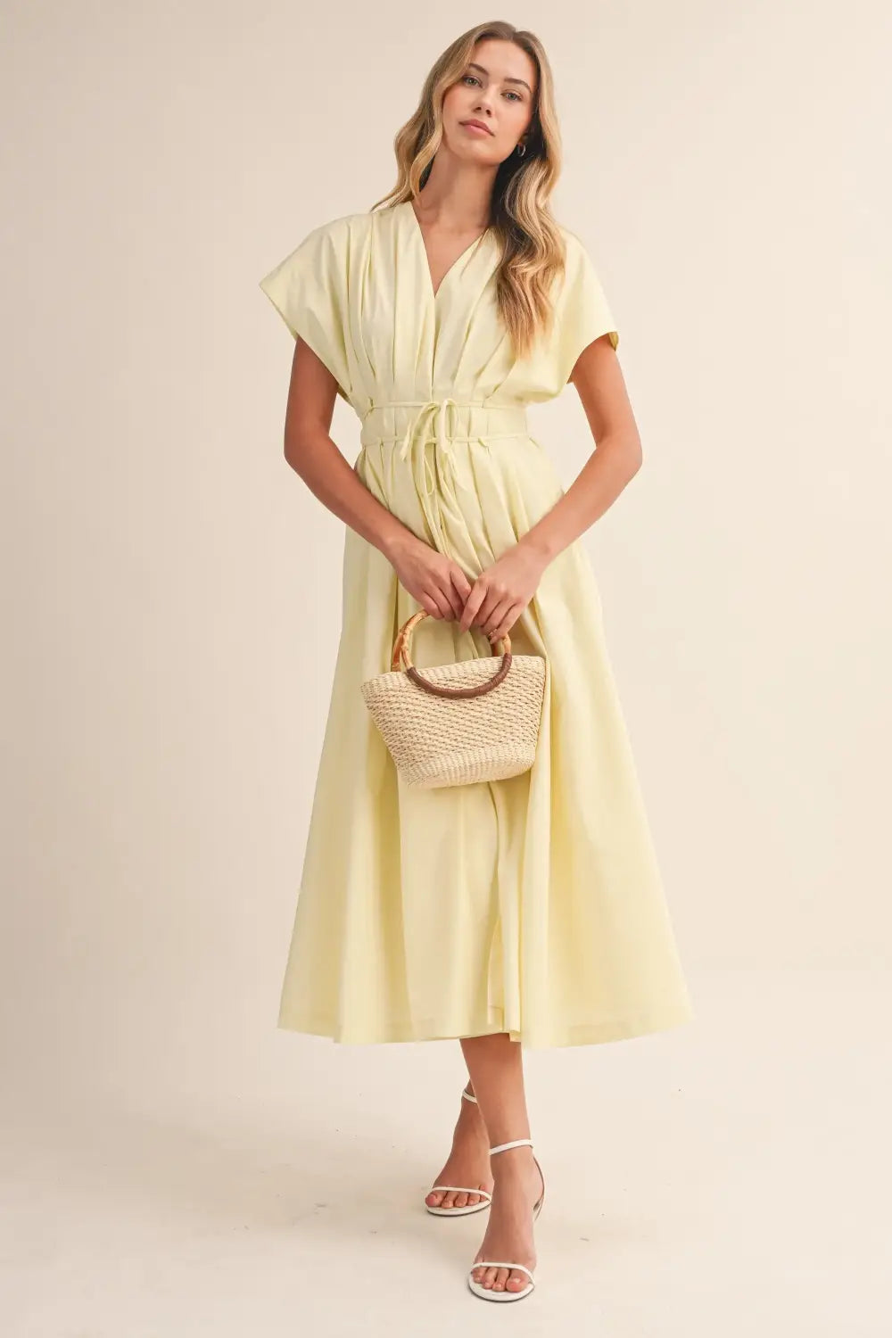 a flowing pale yellow poplin belted maxi dress with v-neckline short draped sleeves and cinched waist belt